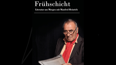 Älterer Mann in Anzug mit rotem Schal und einer Zeitung.
