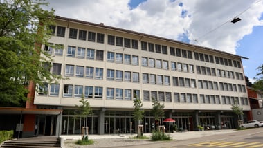 Grosses Bürogebäude mit vielen Fenstern an einem sonnigen Tag.
