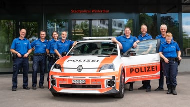 Gruppe von Menschen in blauer Uniform vor einem Polizeiauto.