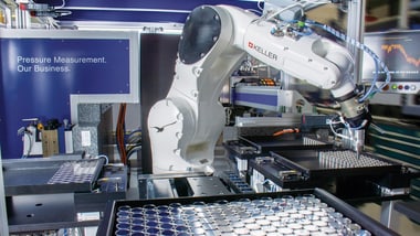 Industrieroboterarm arbeitet an einer Maschine.