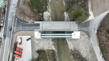 Draufsicht auf eine Brücke über einen Fluss mit umliegender Strasse und Fahrzeugen.