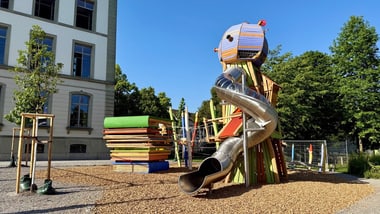 Bild des Spielplatzes "Observatorium" im Stadtgarten beim Schulhaus Altstadt: Spielplatz mit Klettergerüst und Rutsche neben einem Gebäude.