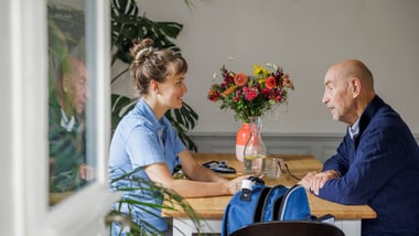 Frau und Mann sitzen an Tisch mit Blumenstrauss.