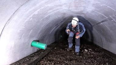 Person mit Helm und Taschenlampe in einem Tunnel.
