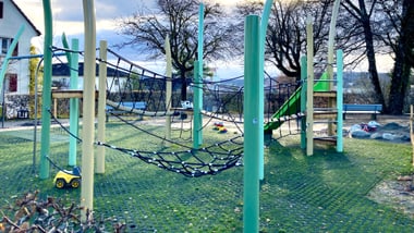 Spielplatz mit Klettergerüst und Rutsche im Freien.