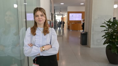Person mit hellblauer Bluse steht in modernem Flur.