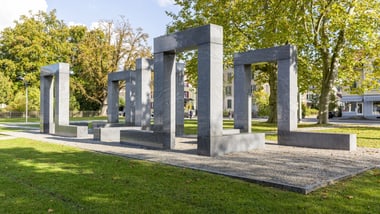 Moderne Steinskulpturen auf einer grünen Wiese in einem Park.