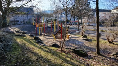 Spielplatz mit buntem Klettergerüst und Bäumen.