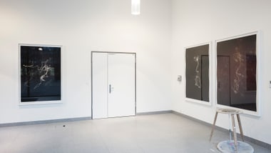 Galeriewand mit drei grossen Bildern und einem Hocker.