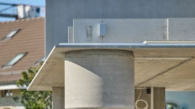 Betonpfeiler und Flachdach vor unscharfem Hintergrund.