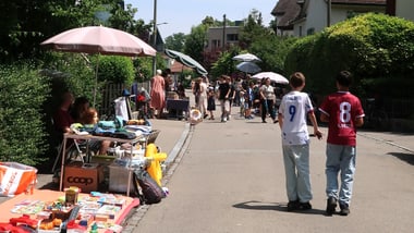 Menschen gehen auf einem Flohmarkt auf der Strasse spazieren.