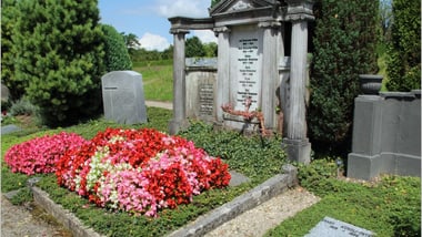 Grosses Familiengrab mit Blumenbeeten und Grabsteinen.