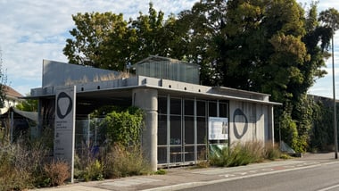 Modernes Gebäude mit Glasdach und Vegetation umgeben.