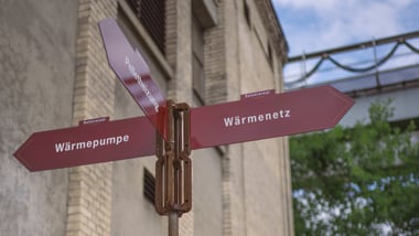 Wegweiser mit rotem Pfeil vor einem Gebäude.