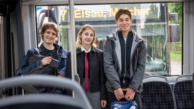 Drei junge Menschen stehen in einem Bus.