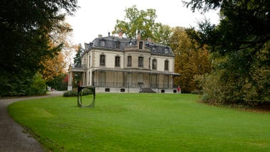 Grosses historisches Gebäude mit Rasen und Bäumen im Vordergrund.