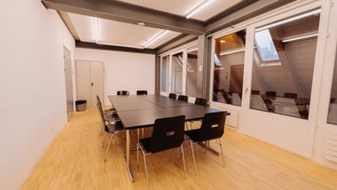 Konferenzraum mit grossem Tisch und Stühlen.