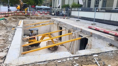 Bauarbeiter in Grube mit kleinem Bagger auf Baustelle.