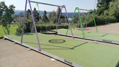 Spielplatz mit Schaukeln auf einem Gummiboden.