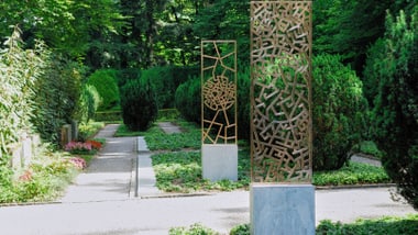 Metallskulpturen in einem gepflegten Garten mit Bäumen.