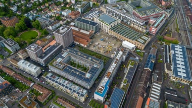 Luftaufnahme eines Stadtgebietes mit Gebäuden, Strassen und Grünflächen.