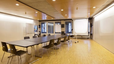 Leerer Besprechungsraum mit Tisch, Stühlen und Projektor.