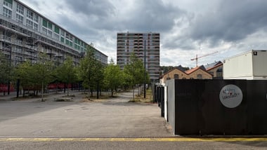 Stadtansicht mit Wohngebäude, Bäumen und Baustelle.