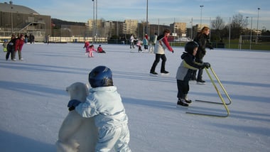 Kinder beim Schlittschuhlaufen auf einer Eisbahn im Freien.