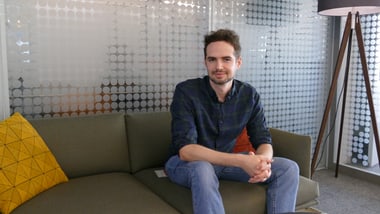 Person auf einem Sofa sitzend in einem modern eingerichteten Raum.
