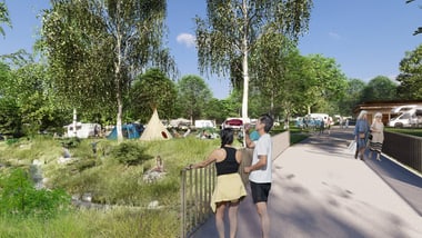 Personen spazieren auf einem Weg neben einem bewaldeten Campingplatz.