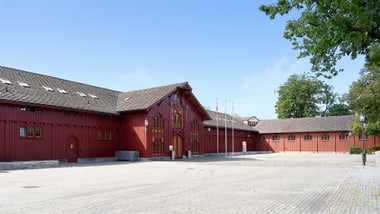 Gebäude MZA Teuchelweiher mit gepflastertem Hof und Bäumen.