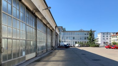 Industriegebäude und geparkte Autos bei sonnigem Wetter.