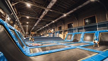 Menschen spielen in einer Trampolinhalle.