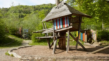 Holzspielhaus in einem bewaldeten Park.