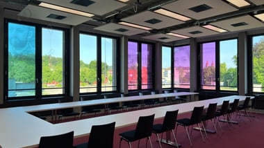 Konferenzraum mit grossen Fenstern und bunten Bildschirmen.
