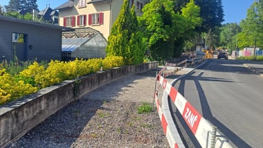 Strasse mit Absperrung und Häusern im Hintergrund.