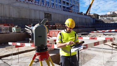 Bauarbeiter mit gelbem Helm bei Baustelle.