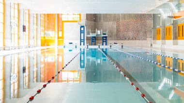 Leeres Hallenbad mit Wettkampfbecken und Startblöcken.