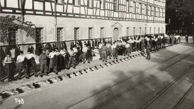 Gruppe von Menschen geht entlang eines Gebäudes mit Fachwerk.