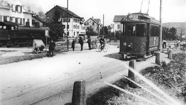 Strassenbahn und Dampflok an einem Bahnübergang 1925 in Römerswil.