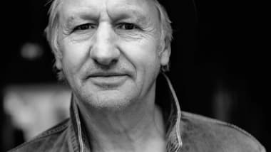 Schwarzweiss-Porträt einer Person mit Hut und Jeansjacke.