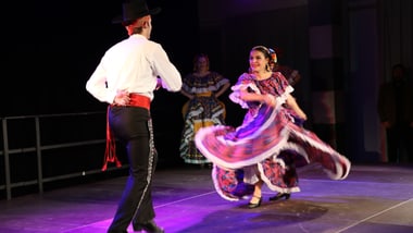 Zwei Personen in traditioneller Kleidung tanzen auf der Bühne.
