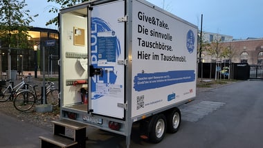 Tauschkabine auf Anhänger mit offener Tür.