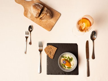 Gedeckter Tisch mit Brot, Suppe und Besteck.