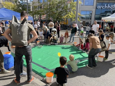 Menschen versammeln sich um ein Spielfeld im Freien.
