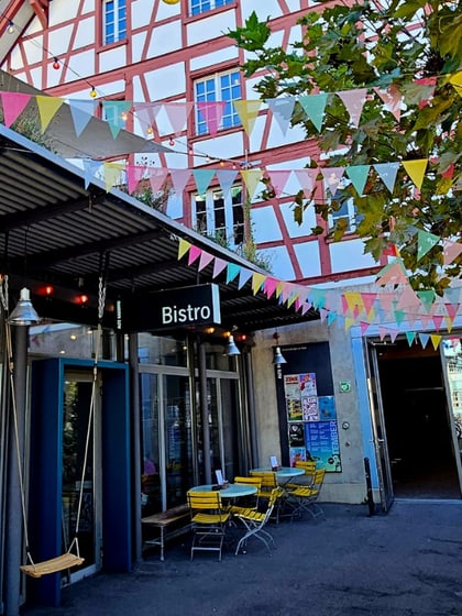 Aussenansicht eines Cafés mit bunten Wimpelketten und Fachwerkgebäude.
