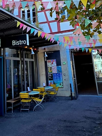 Aussenbereich eines Bistros mit bunten Wimpeln und Stühlen.