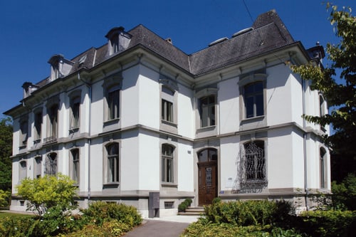 Historisches städtisches Gewerbegebäude mit weissen Wänden und dunklem Dach.