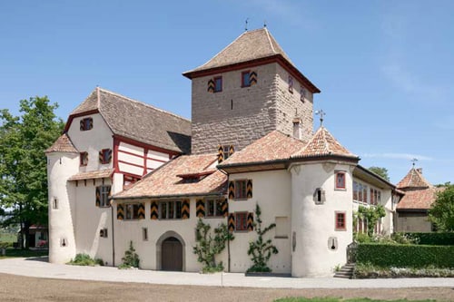 Historisches Schloss mit Türmen und Fachwerk in sonniger Umgebung.