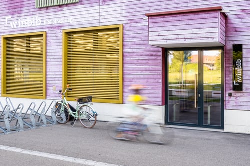 Aussenansicht der Bibliothek Hegi mit lila Holzfassade und Fahrradständern